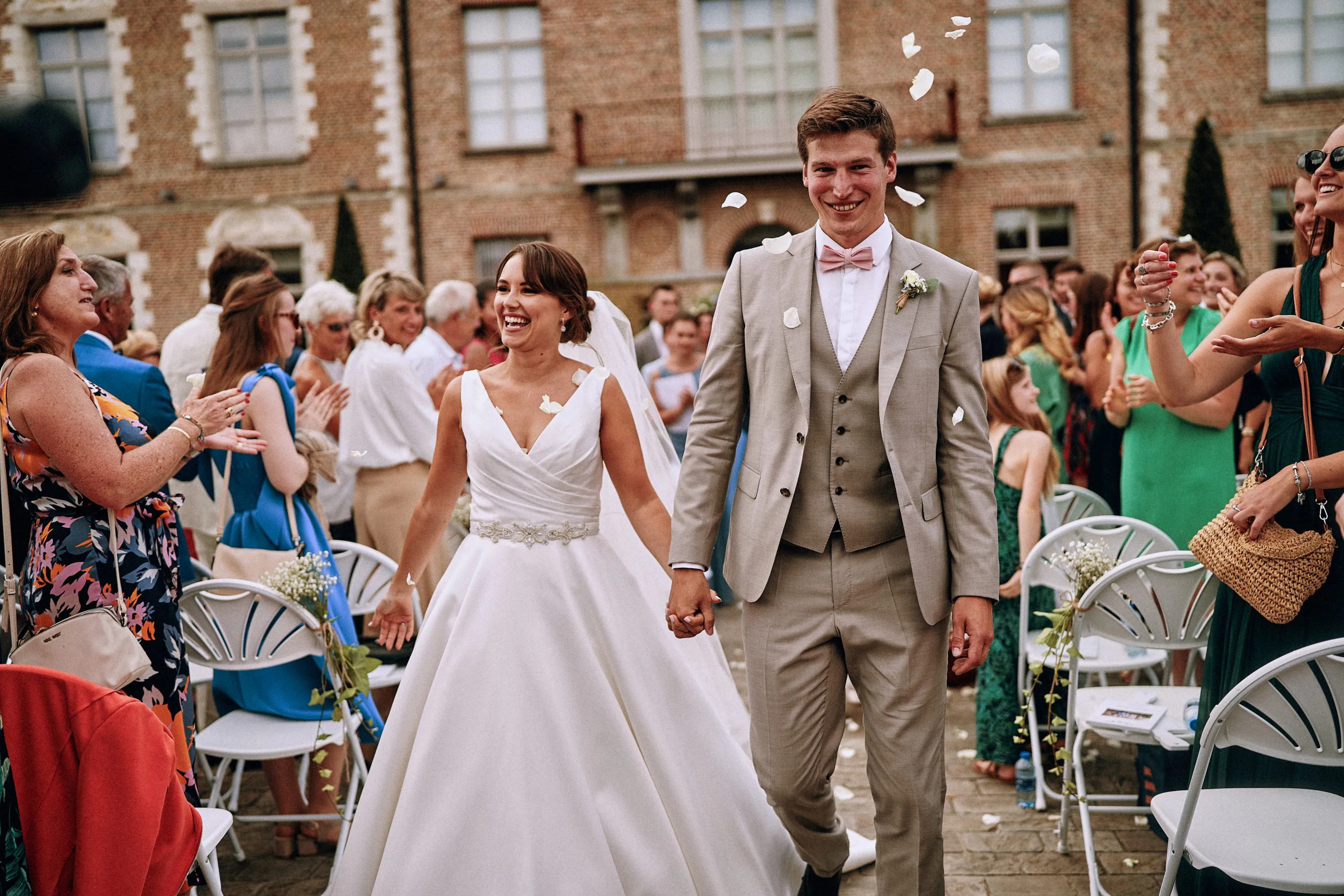 Les mariés de Henin-Beaumont sortant de leur cérémonie laïque sous une pluie de pétales au Château de Morbecque. Photo de mariage par Christophe Blaszkowski, photographe de mariage à Lille.