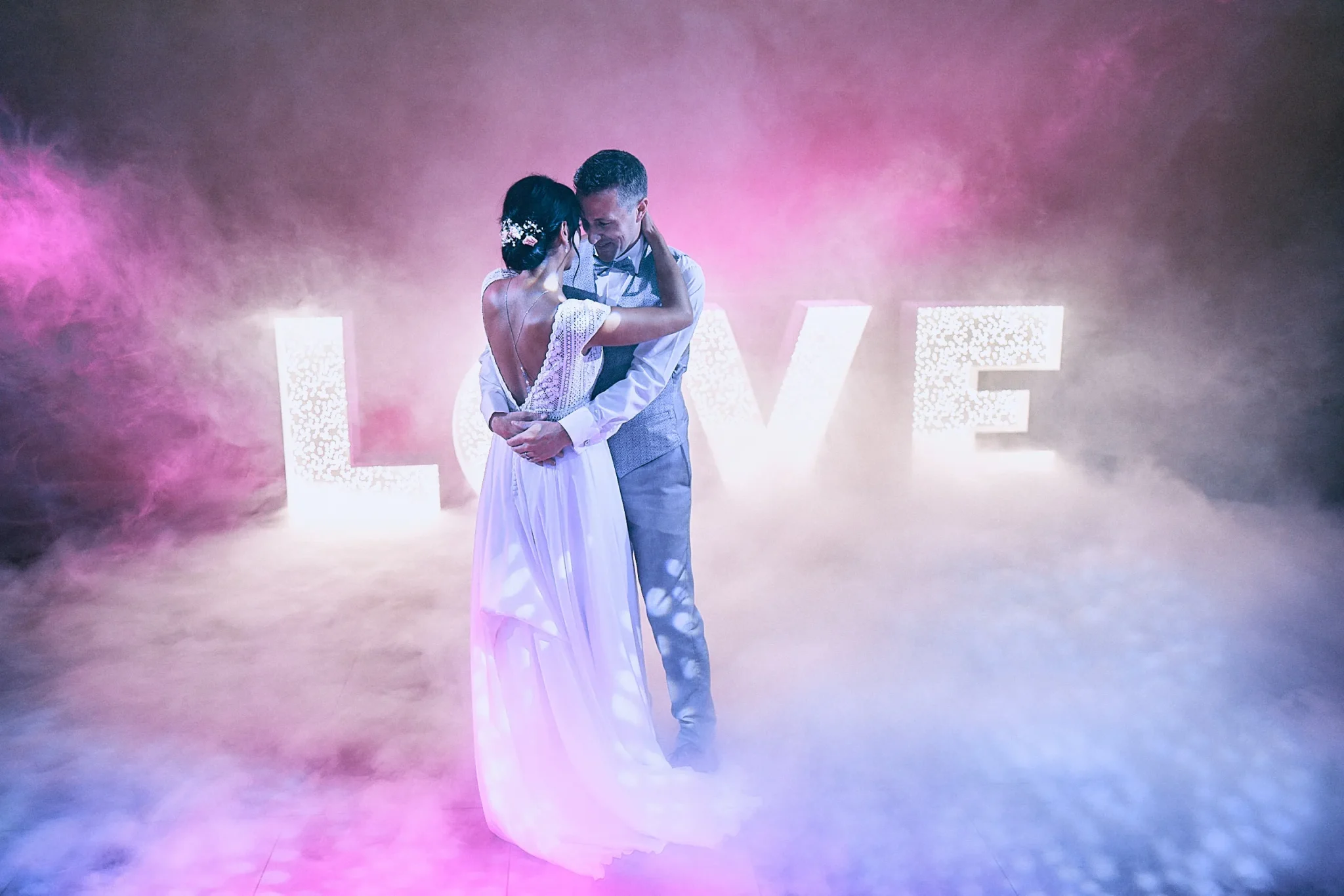 Mariés de Vimy pendant leur première danse à Lille avec fumée lourde et les lettres LOVE en arrière-plan, moment magique et romantique lors de leur mariage