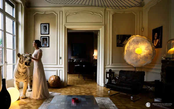 Portrait de la mariée dans un lieu d'art à Lille, avec un tigre blanc en arrière-plan. La photo, qui semble une peinture, intègre la mariée comme faisant partie de l’œuvre. Photo de mariage par Christophe Blaszkowski, photographe de mariage sur Lille.